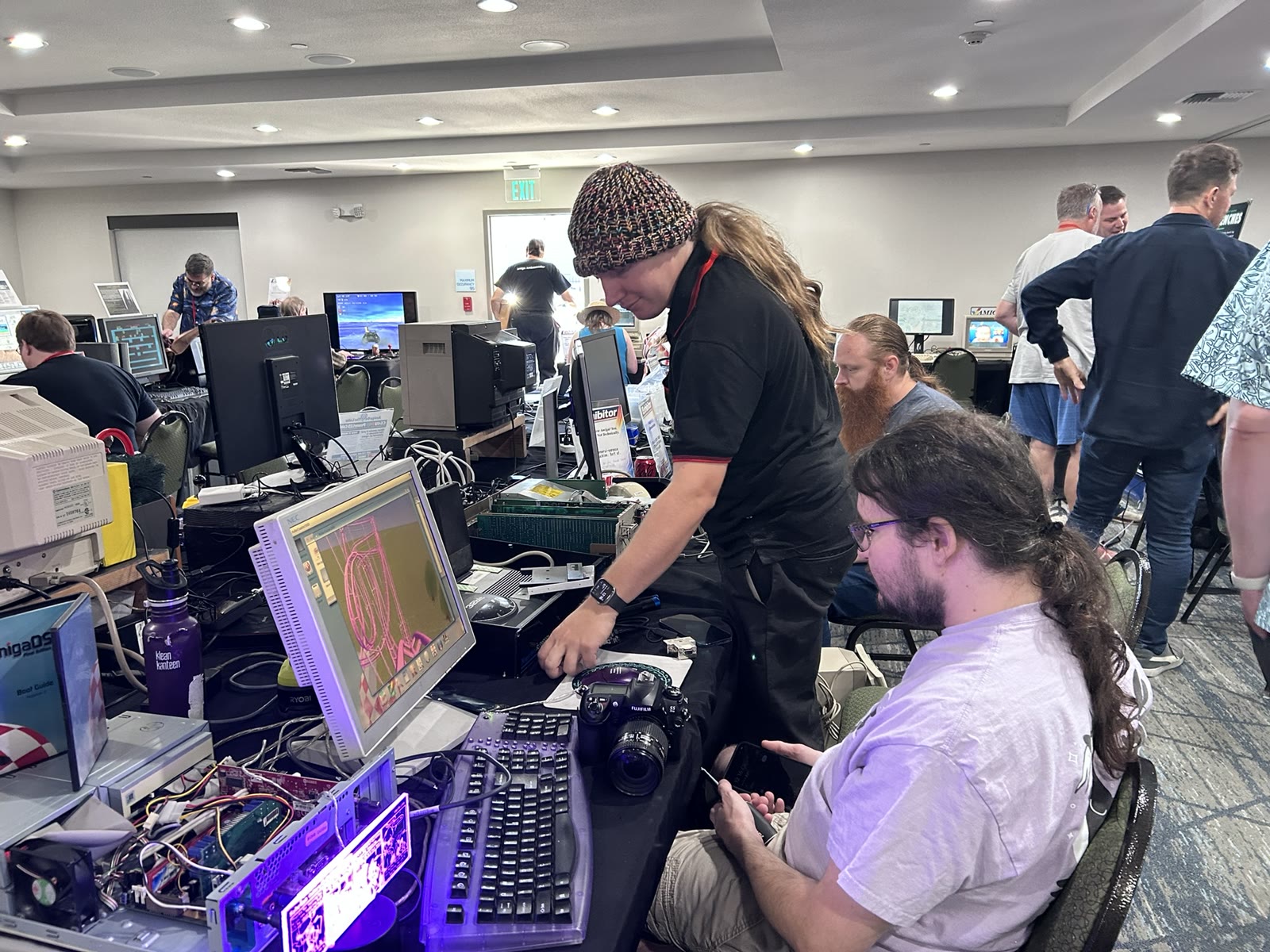 An open computer and a graphics display surrounded by people exploring hardware on the show floor